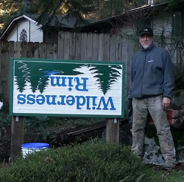 Doug Greathouse standing next to the Wilderness Rim entrance sign, which is mounted upside down.